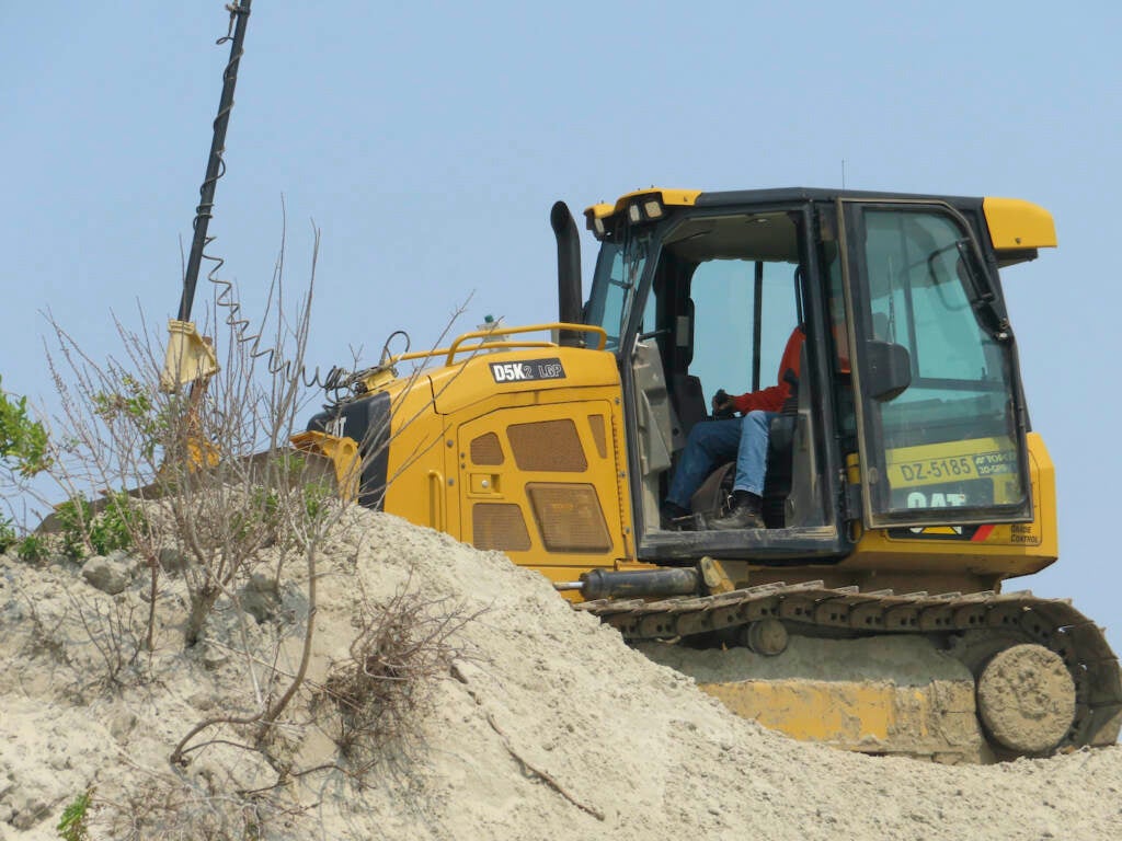 A bulldozer repairs a sand dune
