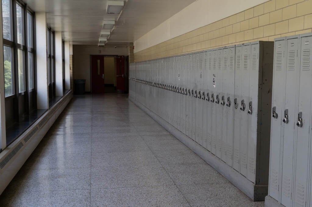 A long hallway in a school, with a wall of lockers.