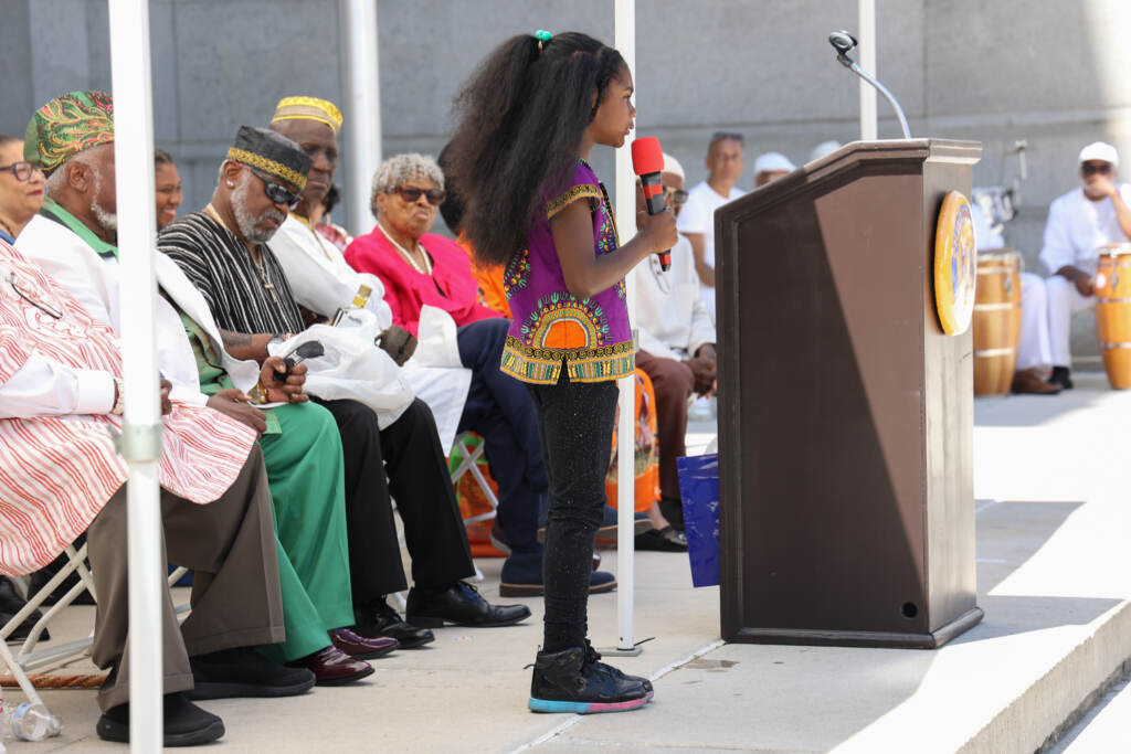 Ava Brown reading on stage into a microphone