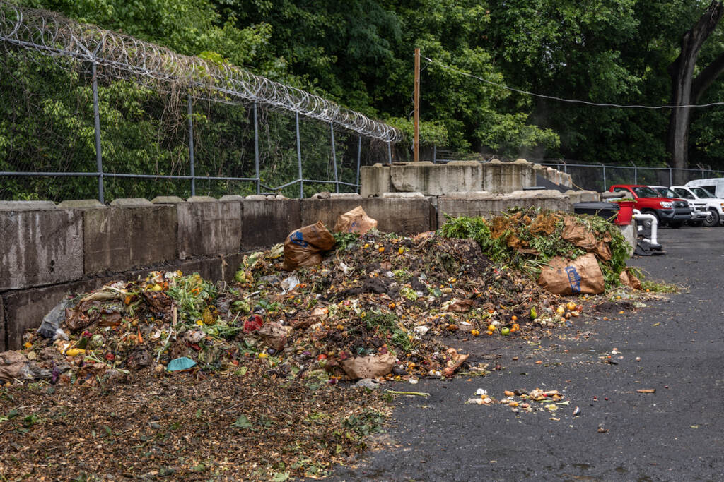 Decomposing food scraps are visible in the outdoor area of a compost facility.