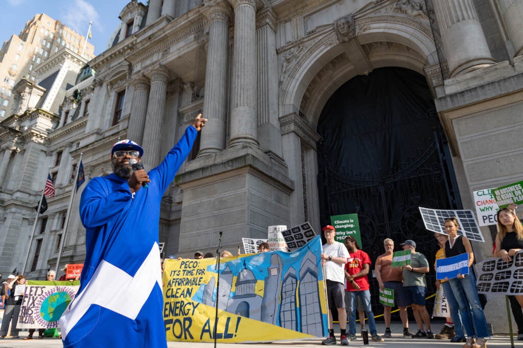 Shawmar Pitts speaking into a microphone at a rally in front of City Hall.