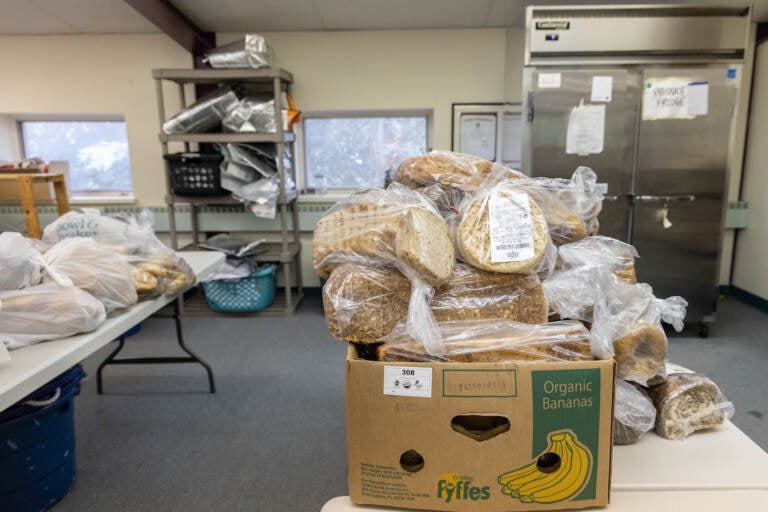 Many bags of bread sit on a table in the food bank.