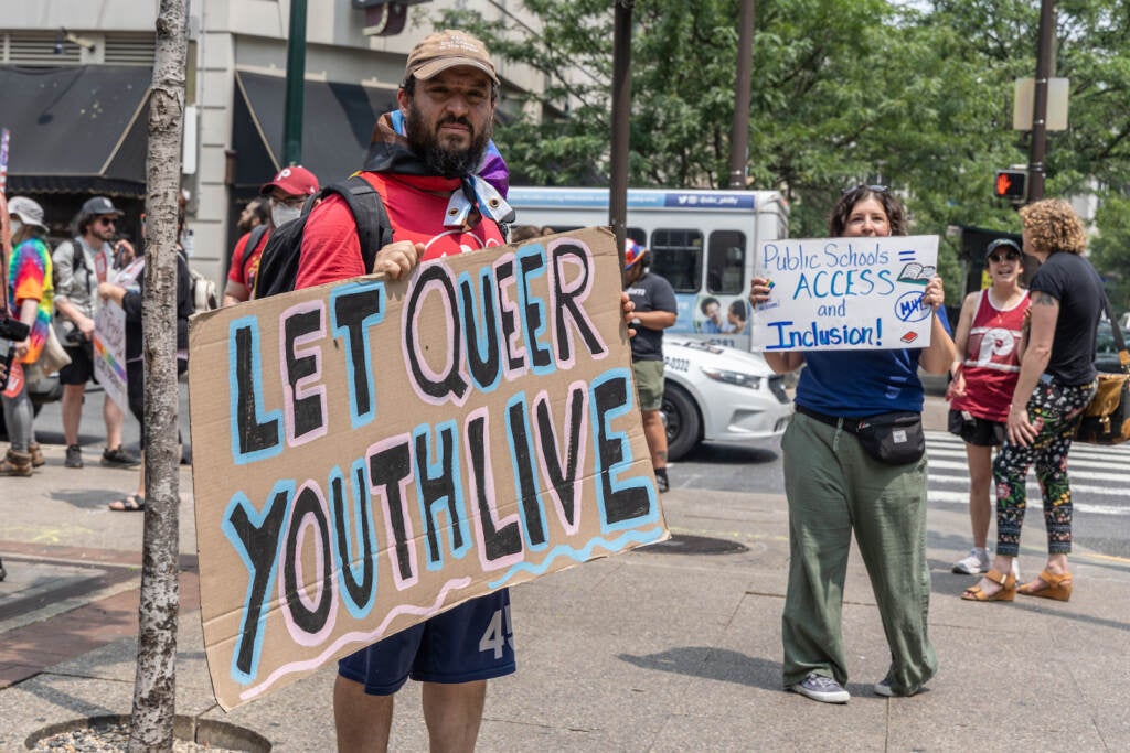 Andrew Saltz stands with a sign that reads ''Let queer youth live''