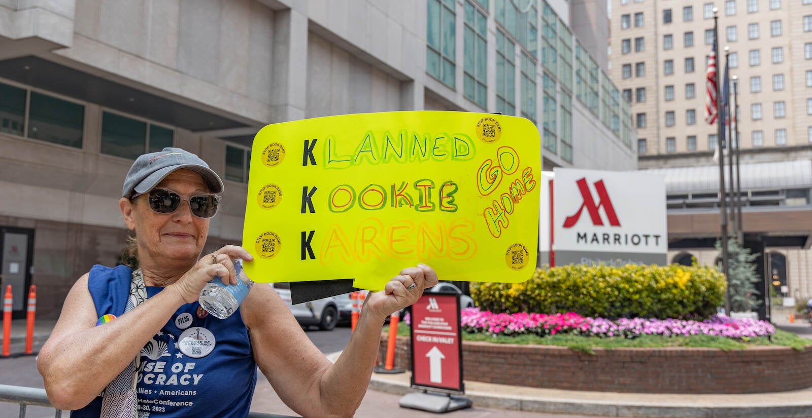Jackie Ellenberger holds up a sign outside the Moms for Liberty summit that reads, ''Klan Kookie Karens go home''