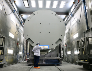 A worker stencils the destination on to fuel storage module at Holtec International in Camden. This one is headed for D.C. Cook Nuclear Plant in Michigan. (Emma Lee/WHYY)