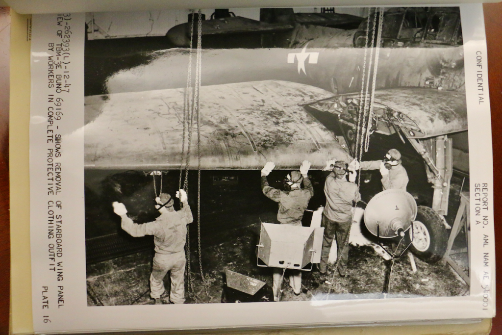 In a photo from the J. Hartley Bowen papers at the Science History Museum, workers in protective clothing remove a wing panel from a contaminated plane. (Emma Lee/WHYY)