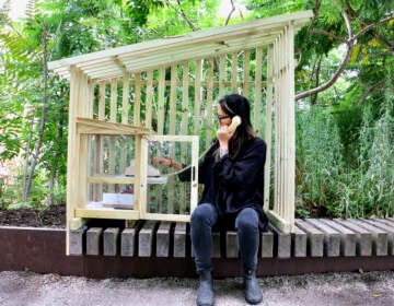 Annie Chiu-McCabe dials a rotary phone inside a wooden structure at the Rail Park.