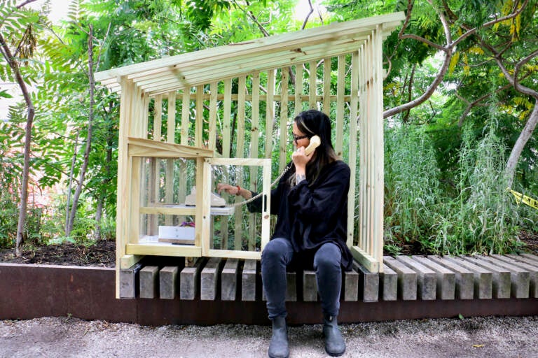 Annie Chiu-McCabe dials a rotary phone inside a wooden structure at the Rail Park.