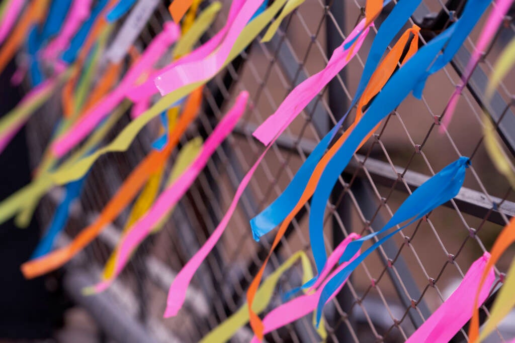 Multicolored ribbons tied to a fence flutter in the wind