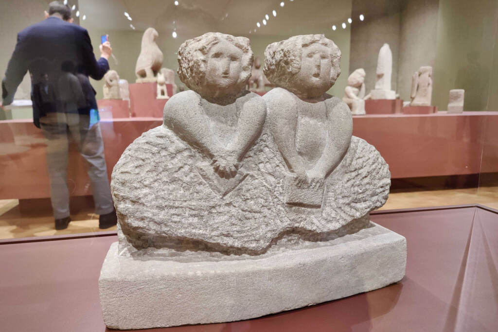 A sculpture of William Edmondson depicting two women next to one another is displayed in a gallery.