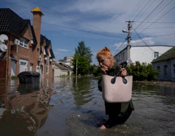 A local resident makes her way through a flooded road after the walls of the Kakhovka dam collapsed overnight, in Kherson, Ukraine