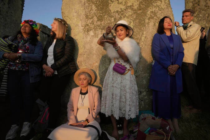 Revelers meditate next to stones at sunrise as thousands gather at the ancient stone circle Stonehenge to celebrate the Summer Solstice, the longest day of the year, near Salisbury, England, Wednesday, June 21, 2023. (AP Photo/Kin Cheung)