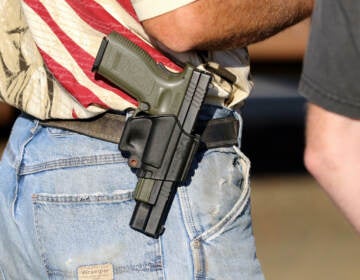 In this Oct. 9, 2015 file photo, Michael Johnson wears a firearm as he waits outside of Roseburg Municipal Airport in Roseburg, Ore.