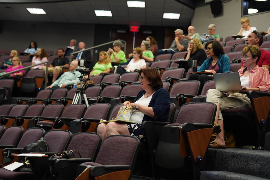 People sitting in an auditorium watching a presentation.