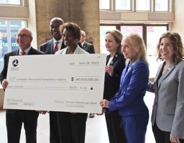 U.S., city, and transit leaders hold up a check for $80 million which will go towards SEPTA's goal of having a zero-emission fleet of buses