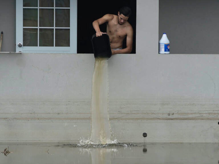 Man dumping water out of home in Catano, Puerto Rico