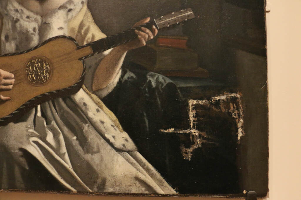An upclose view of the guitar in the painting, "Lady with a Guitar," marred by a tear