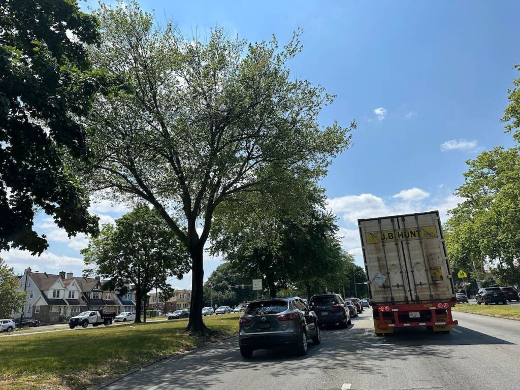 A view of cars and trucks on a road in a residential area.