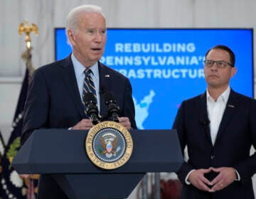 Biden speaks at a podium as Shapiro looks on.