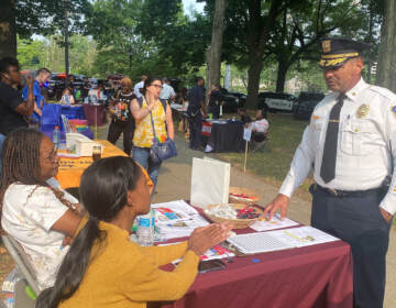 Chief Campos speaking with 2 women sitting at a desk at the fair.