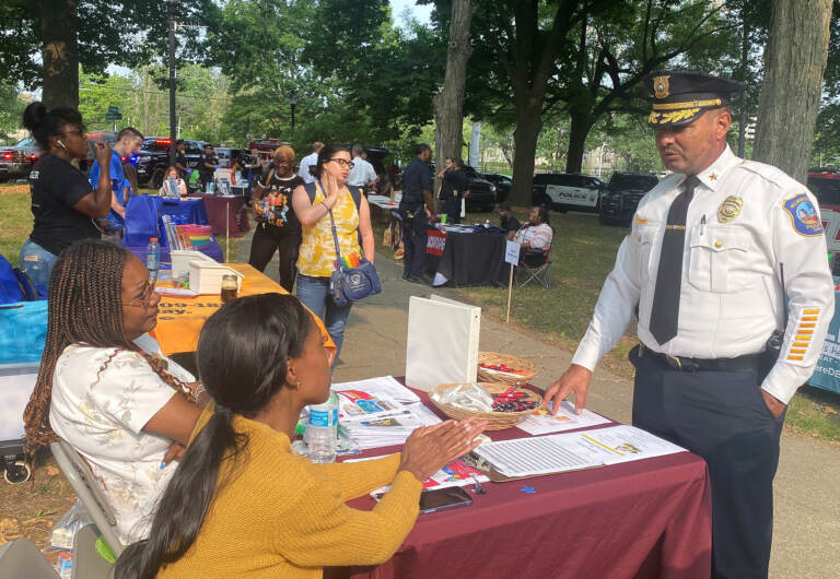 Chief Campos speaking with 2 women sitting at a desk at the fair.