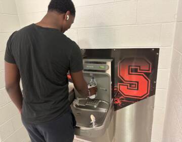 A student puts his water bottle under a filtering station.