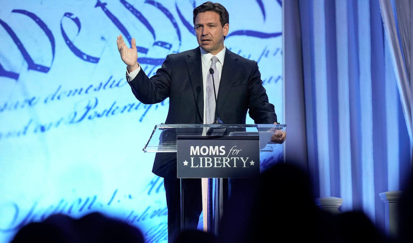 Ron DeSantis speaking at a podium at the Moms For Liberty conference