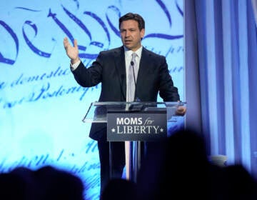 Ron DeSantis speaking at a podium at the Moms For Liberty conference