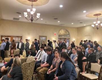 A room of people seated in chairs at a funeral home.