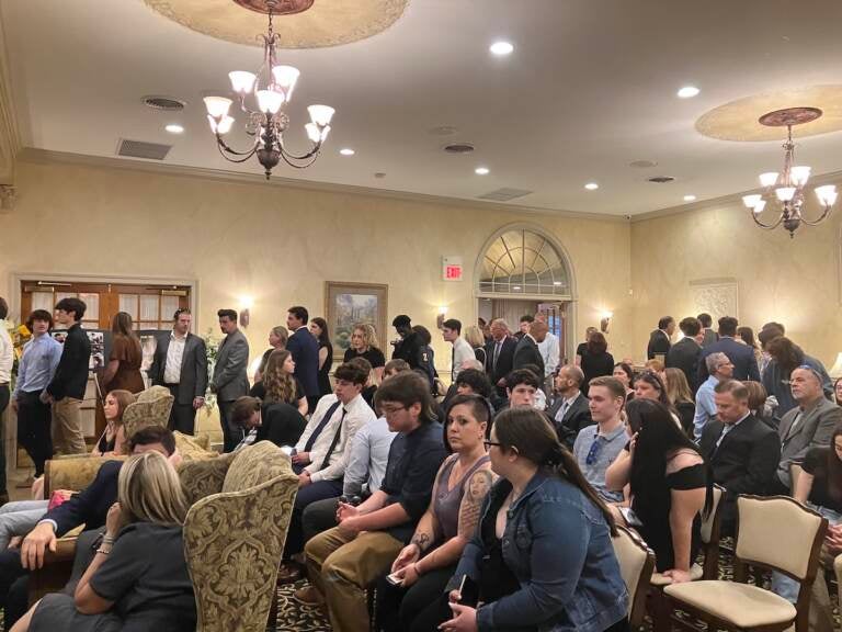 A room of people seated in chairs at a funeral home.