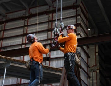 Construction workers work on a scaffolding.