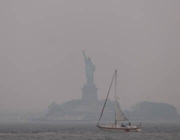 The Statue of Liberty stands shrouded in a reddish haze as a result of Canadian wildfires