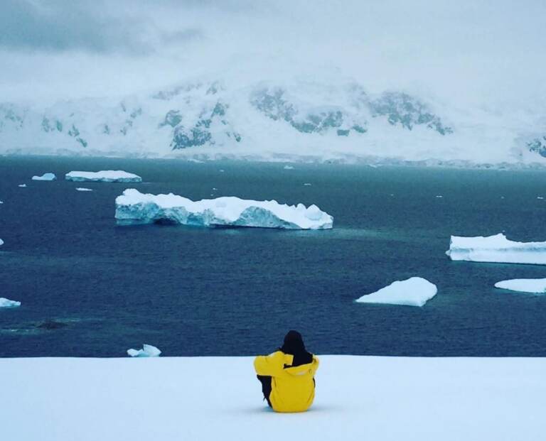 Lawrence Phillips sitting and looking out on the ocean and icebergs.