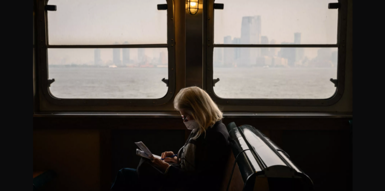 A passenger wearing a face mask rides the Staten Island Ferry past the Manhattan skyline during heavy smog in New York