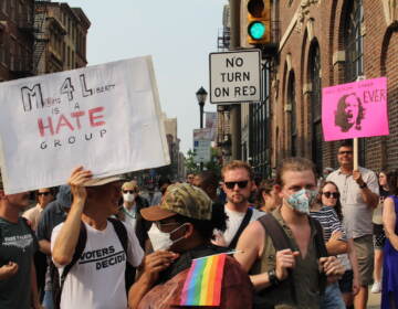 People hold up signs protest Moms for Liberty.