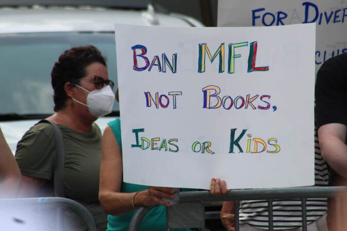 A person holds a sign that reads 