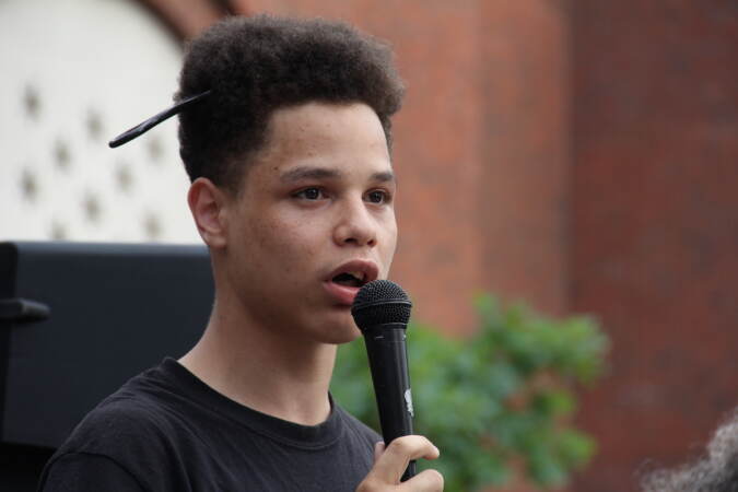 Jazmyn Henderson's 17-year-old son, Noble, leads chants and speaks into a microphone.