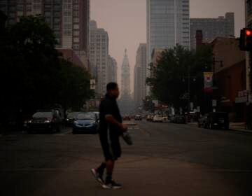 A man crossing the street, with a very hazy sky