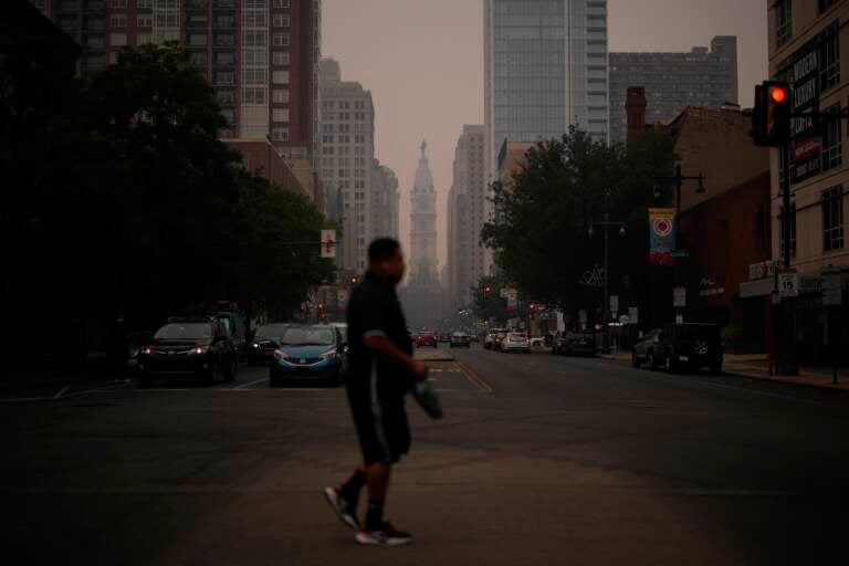 A man crossing the street, with a very hazy sky