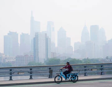 A person cycles past the skyline in Philadelphia shrouded in haze, Thursday, June 8, 2023.