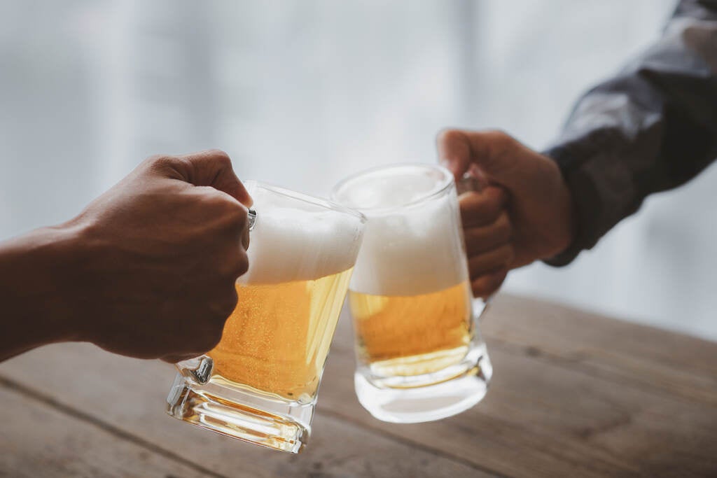 Two people clink glasses of beer at a table.