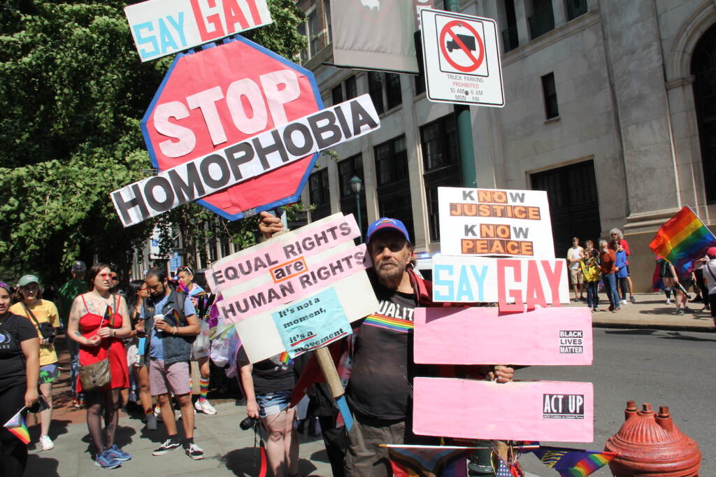 A man holding many pro-LGBTQ signs