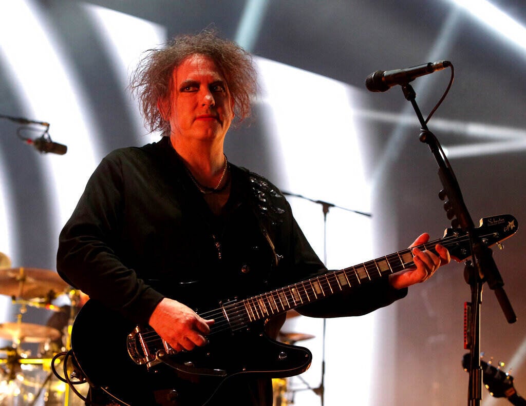 Robert Smith of The Cure plays guitar onstage.