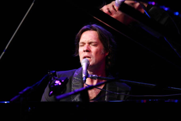 Rufus Wainwright sings while playing the piano.