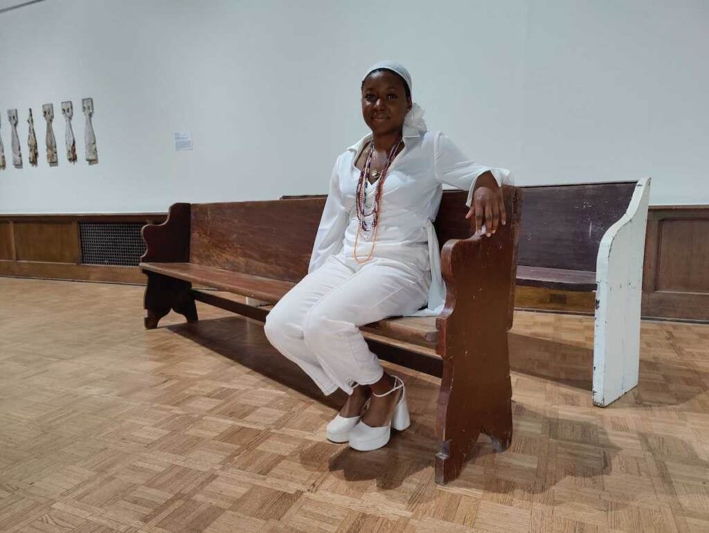 Artist Adebunmi sits on a pew salvaged from the Old Jerusalem Church