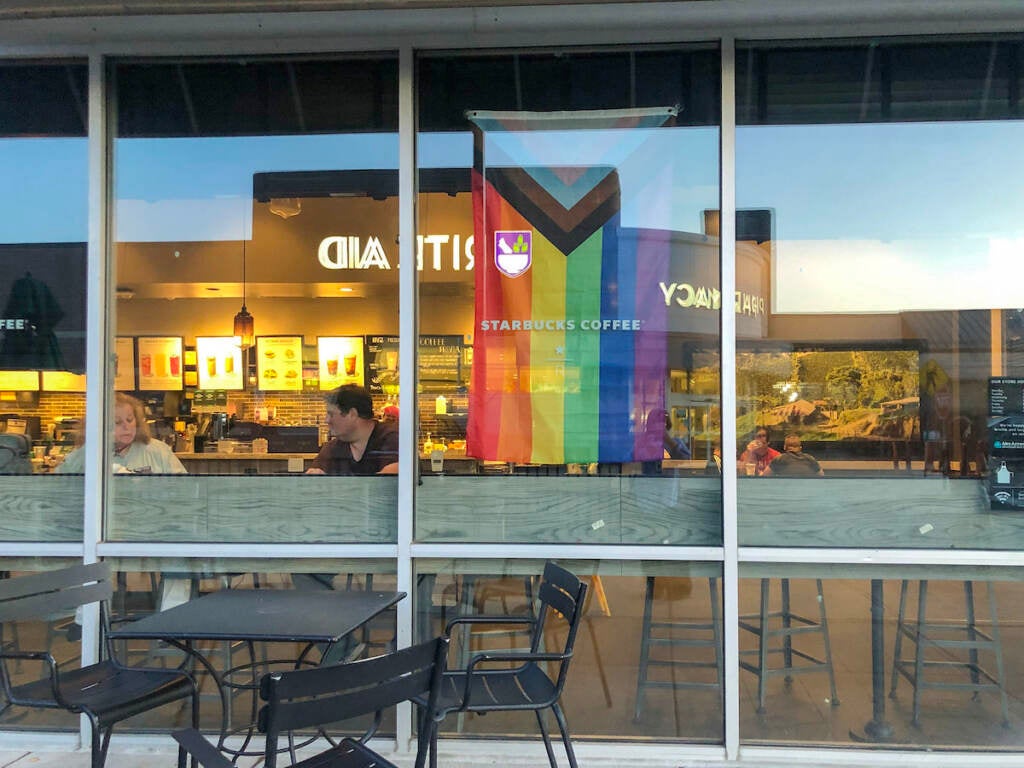 A Pride flag hangs in the window of a Starbucks store.