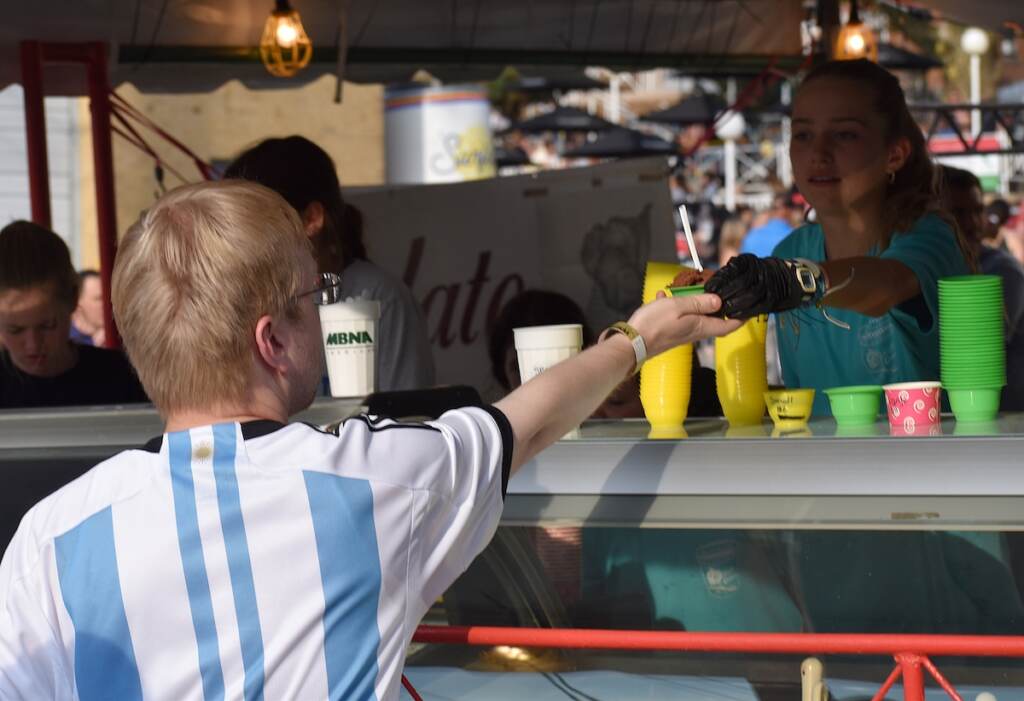 A person reaches out their hand to take a gelato from a vendor.