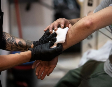 A nurse treats a man's skin wounds.