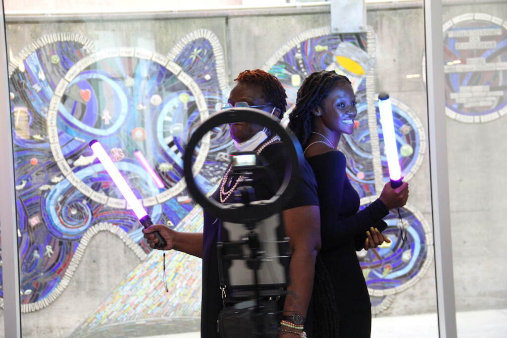 Two people stand side-by-side as they use a 360-degree camera.