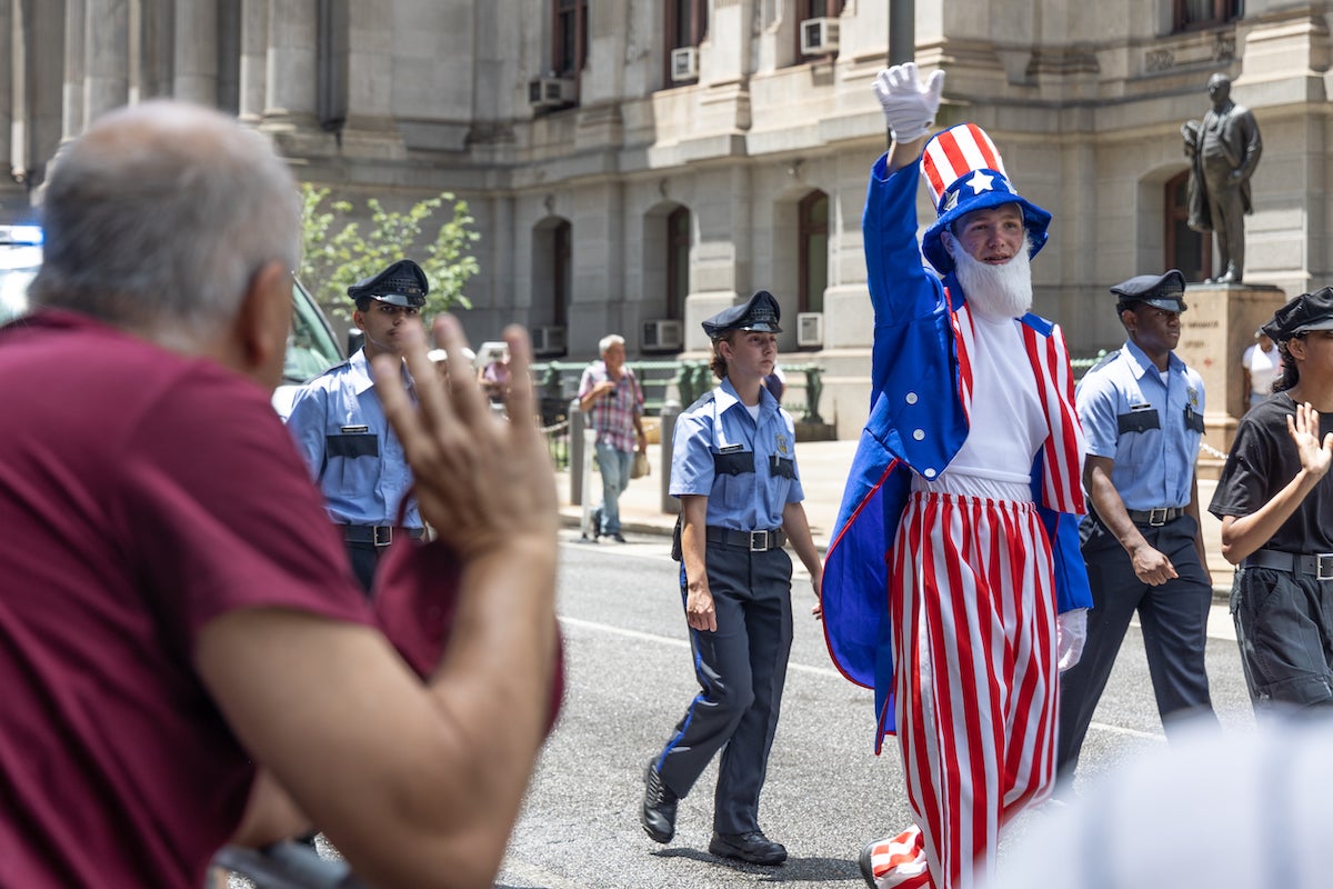 Someone dressed as Uncle Sam and officers walk by City Hall in the parade.